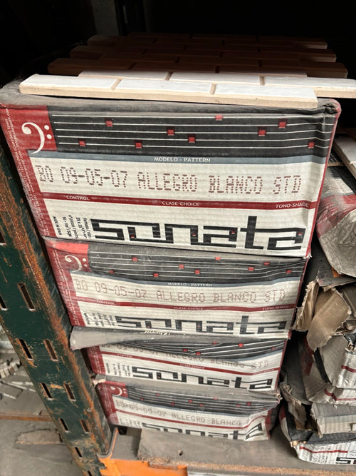 A stack of printed paper sheets or booklets labeled 'sonata' and 'Allegro Blanco Std' on a pallet in a warehouse-like setting.