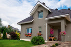 Gray house with decorative plants on a sunny day