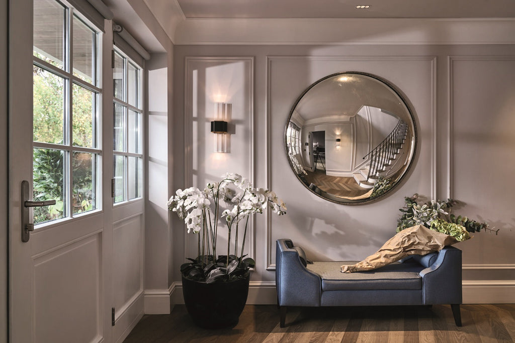 Modern interior with a round mirror, sofa, and decorative plants.