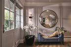 Modern interior with a round mirror, sofa, and decorative plants.