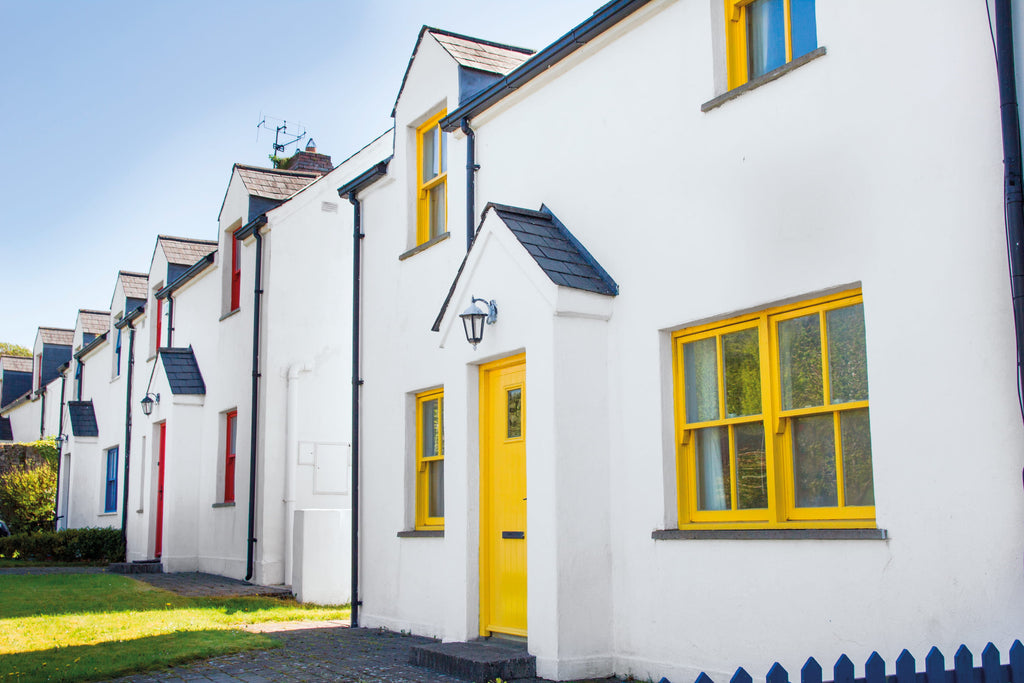 Row of white houses with yellow doors and windows on a clear day.