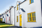 Row of white houses with yellow doors and windows on a clear day.