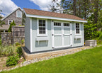 Small shed with white exterior and brown roof in a garden setting