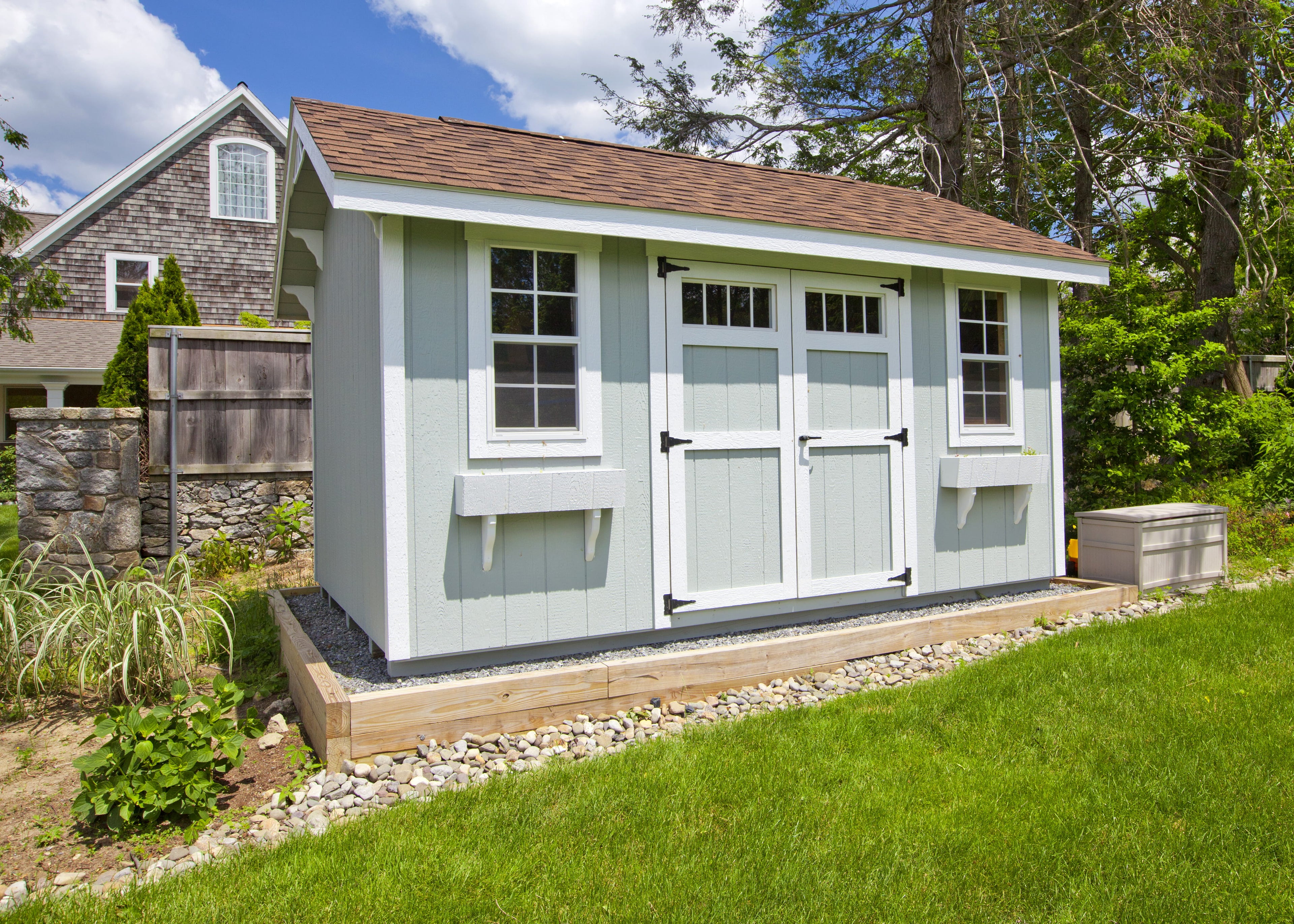 Small shed with white exterior and brown roof in a garden setting