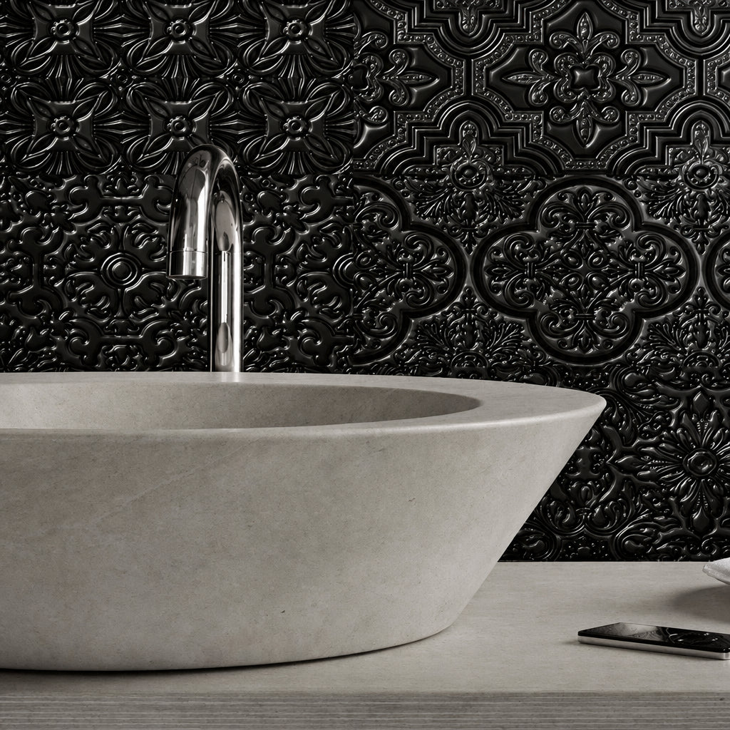 A modern bathroom scene featuring a large concrete vessel sink with a chrome faucet, set against a textured blue-gray embossed tile wall. A white teacup and saucer sit on the counter next to a smartphone.