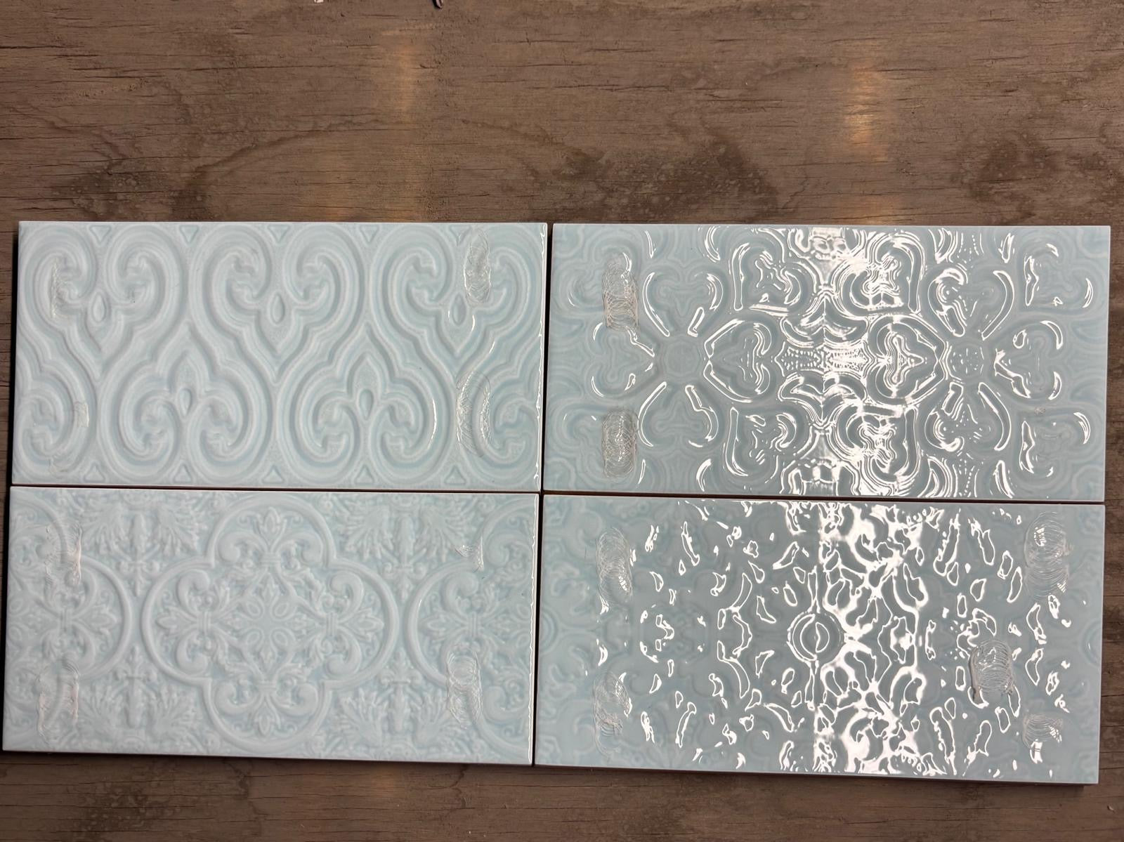 Four decorative tiles with embossed patterns