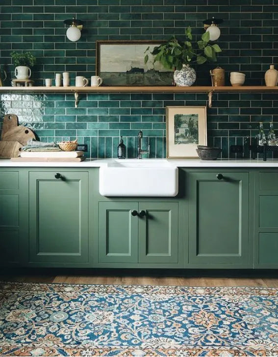 Green kitchen with green tiles, white sink, and wooden shelves.