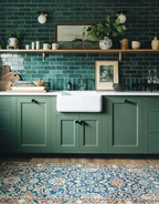 Green kitchen with green tiles, white sink, and wooden shelves.