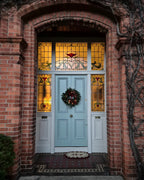 Light blue door with stained glass panels on a brick wall
