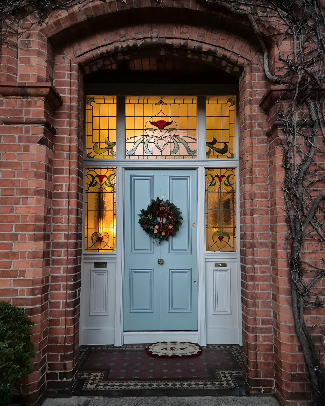 Light blue door with stained glass panels on a brick wall