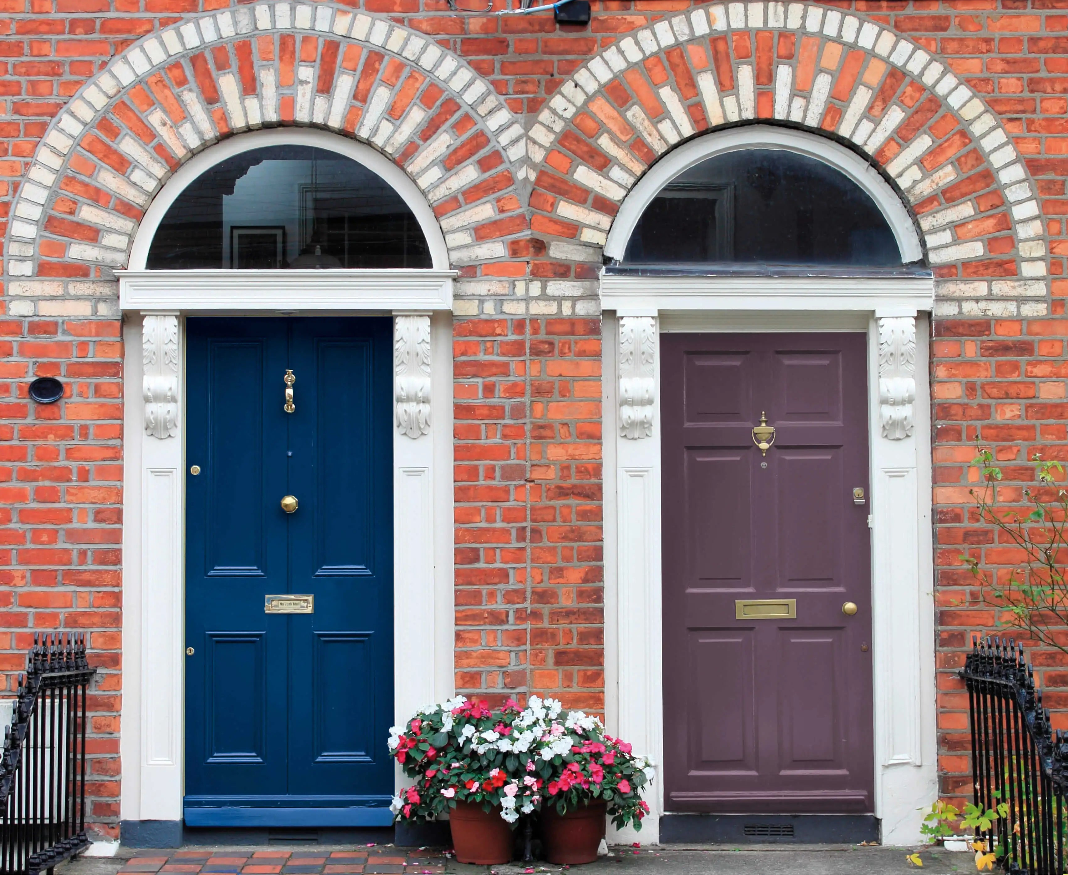 Two doors on a brick building, one blue and one purple, with decorative elements.