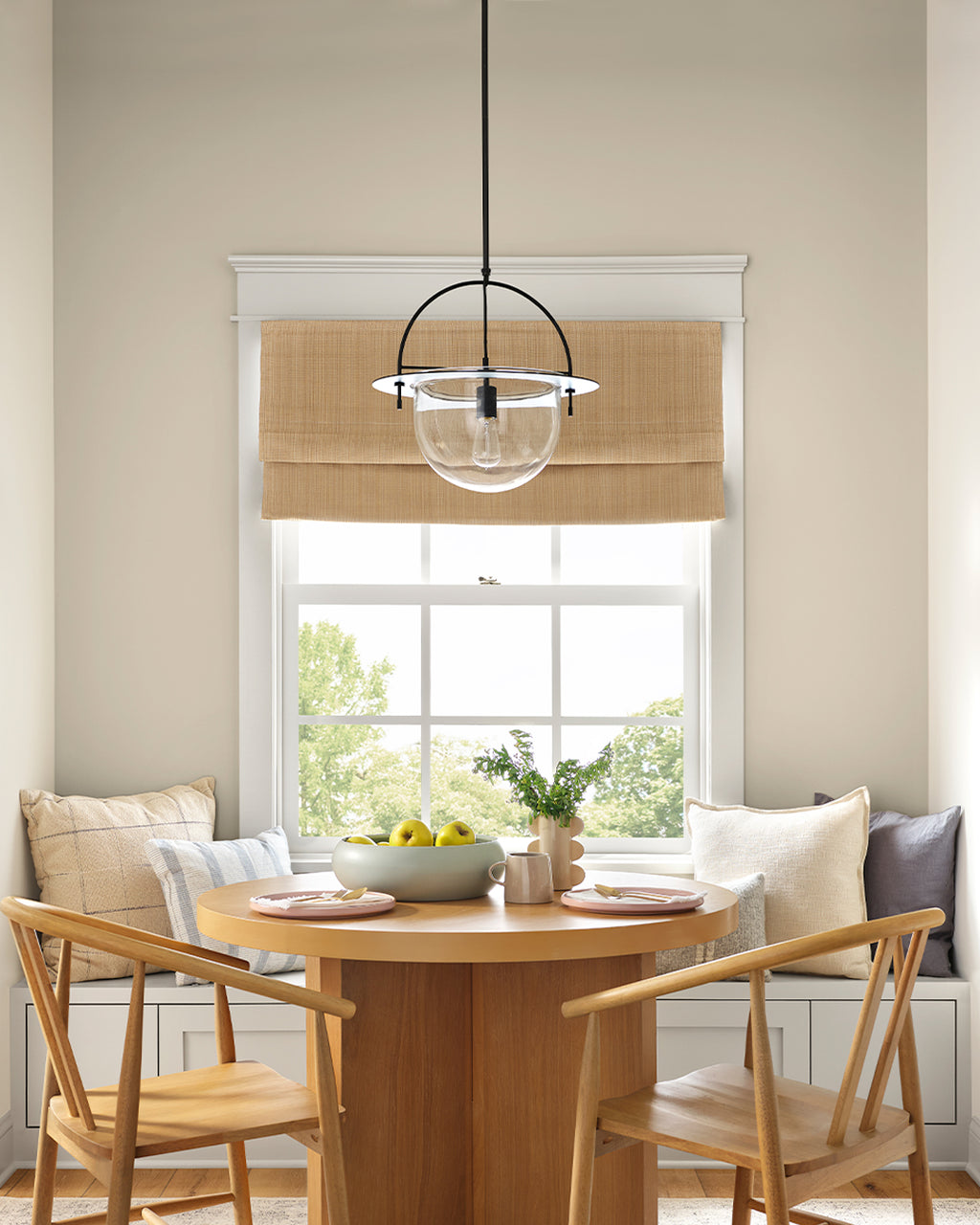 Dining area with wooden table and chairs, large window with light brown blinds, and a pendant light.