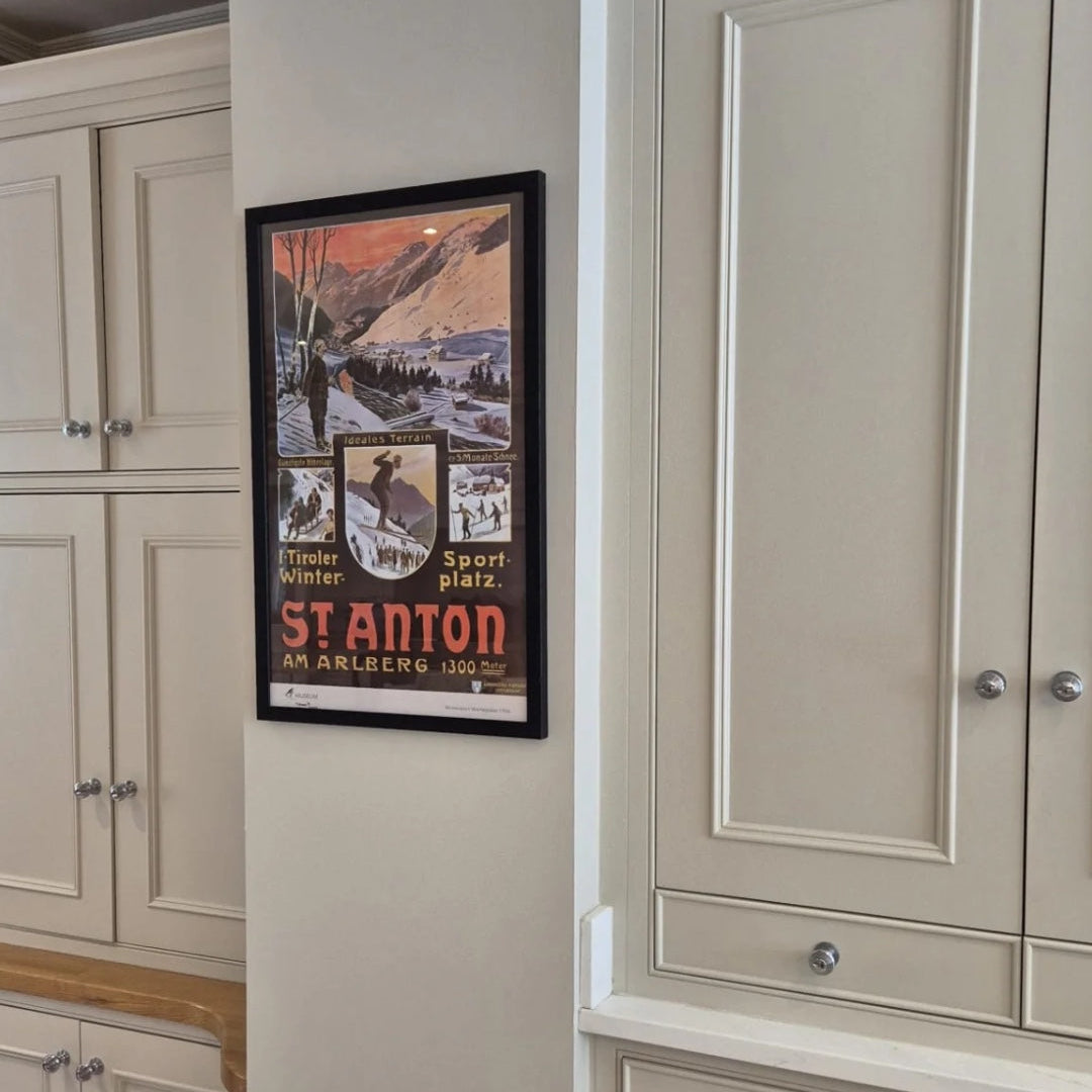 Framed St Anton poster on a wall between beige cabinets