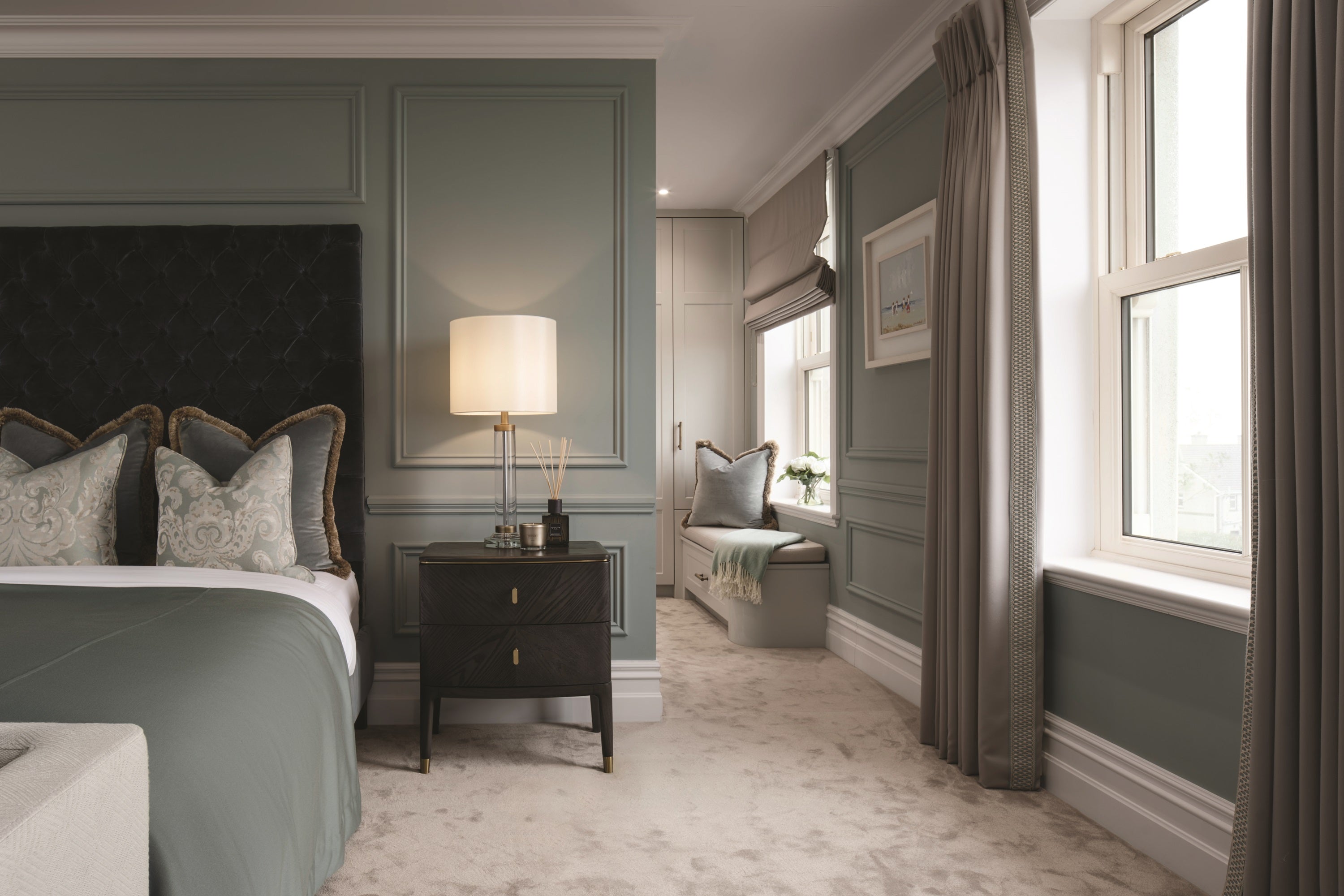Luxurious bedroom with dark upholstered bed, nightstand, and large window.