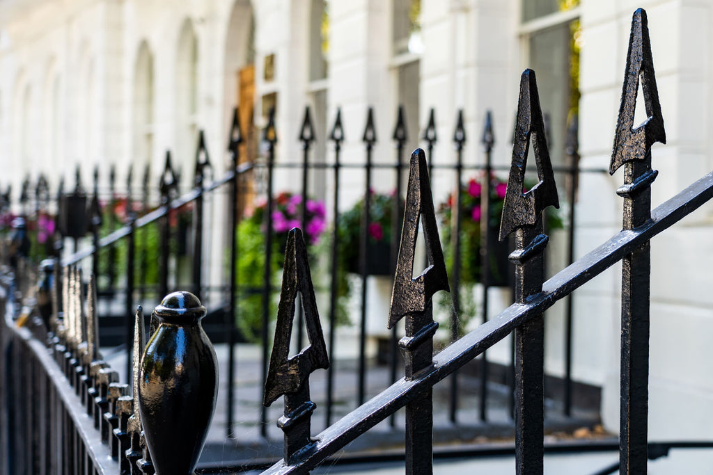 Decorative black metal fence with intricate designs in front of a building with large windows.