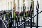 Decorative black metal fence with intricate designs in front of a building with large windows.