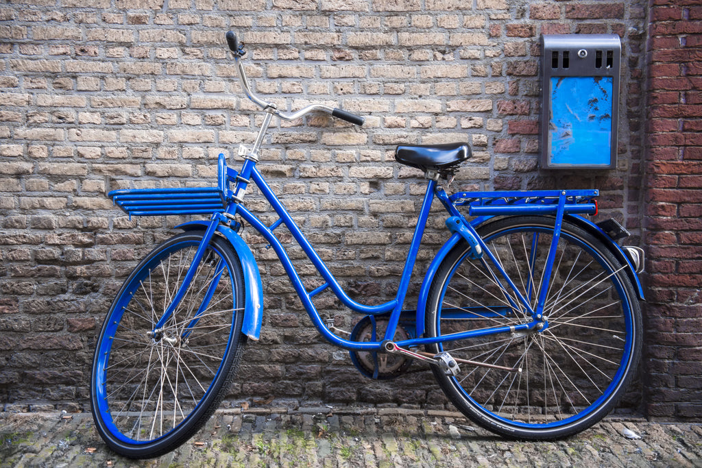 Blue bicycle leaning against a brick wall.