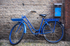 Blue bicycle leaning against a brick wall.