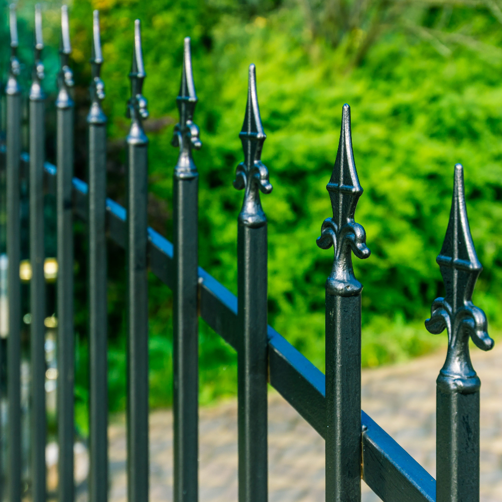 Black metal fence with decorative spikes against a green blurred background