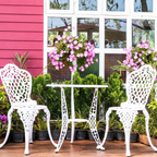 White metal chairs and table set on a wooden deck with pink wall and window in the background
