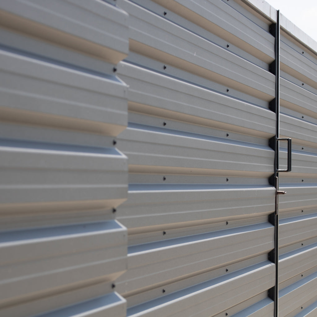 Metal storage shed with corrugated siding and a door handle.
