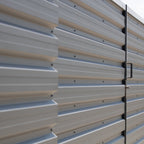 Metal storage shed with corrugated siding and a door handle.