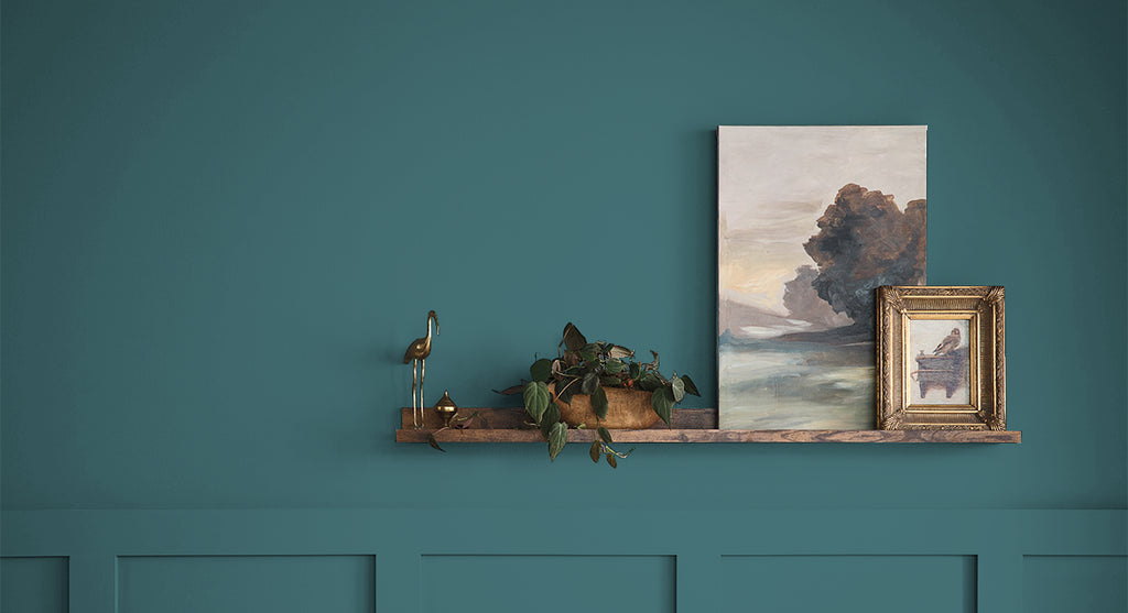 Decorative shelf with framed artwork against a teal wall