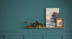 Decorative shelf with framed artwork against a teal wall