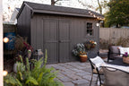 Backyard with a gray shed, outdoor furniture, and potted plants.