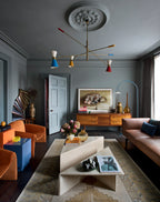 Modern living room with a colorful chandelier, gray walls, and a brown sofa.
