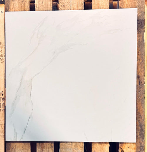 A square white marble-look tile with soft gray veining, displayed flat on a rustic wooden slatted surface.