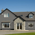 Gray house with stone entrance and green grass in front