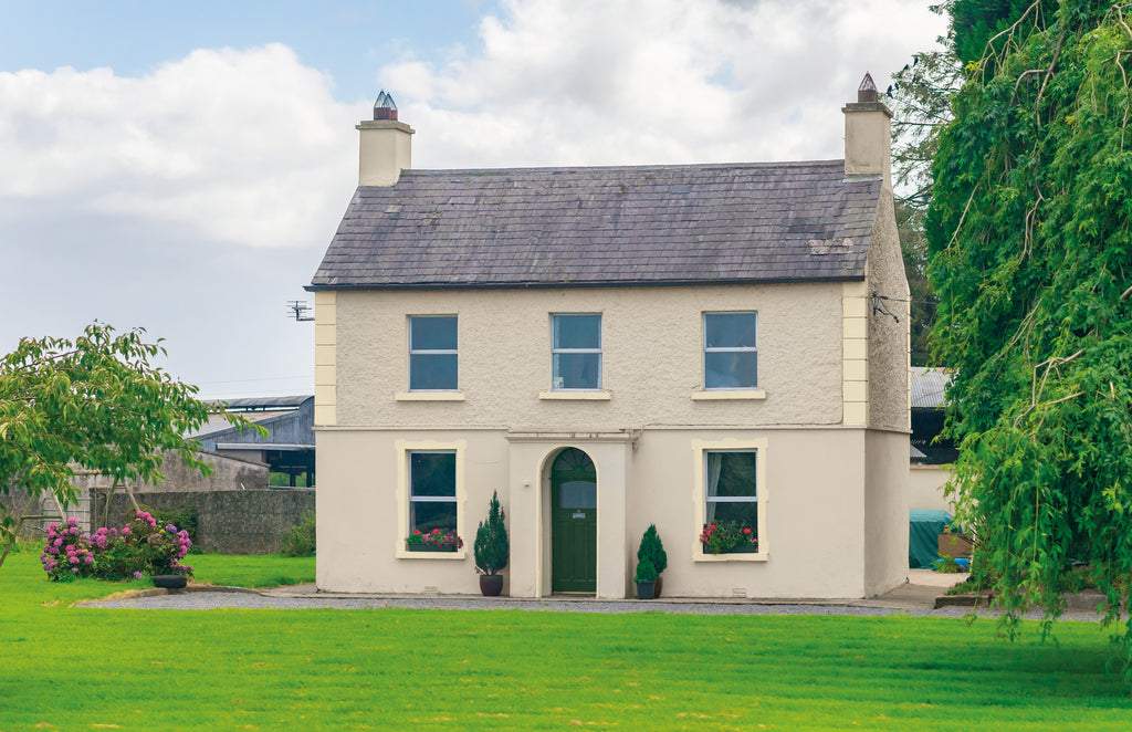 Stately home with a well-maintained garden and trees on a clear day