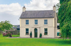 Stately home with a well-maintained garden and trees on a clear day